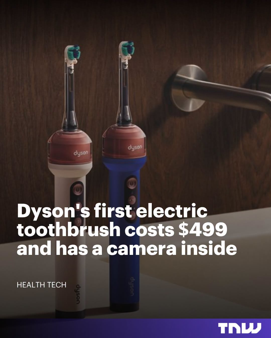 Two Dyson electric toothbrushes, one white and one blue, stand upright on a bathroom counter next to a chrome towel bar.